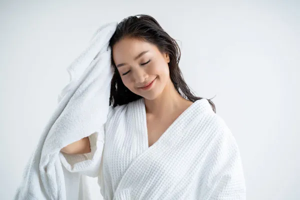A woman scrubbing her hair using a white towel